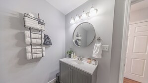 A bathroom with a vanity, a mirror, and a towel rack.