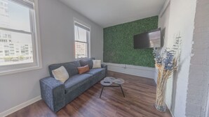 A modern living room with a grey sofa, a small round coffee table, and a green textured wall.