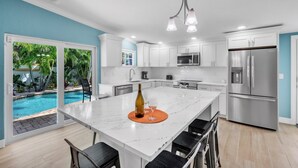 A modern kitchen with white cabinets, stainless steel appliances, and a large island with bar stools.
