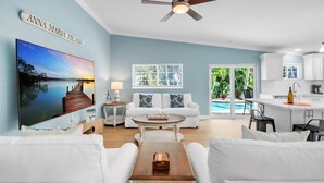 A modern living room with a white sofa, a coffee table, and a ceiling fan.