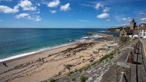 A coastal beach with a stone wall, a church, and a clear sky. - Perfectly located to enjoy breathtaking sea views of Porthleven beach  & harbour (Porthleven)