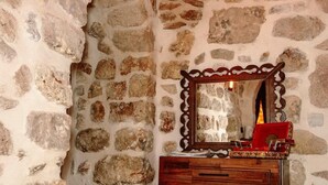 A stone-walled room with a wooden dresser and a mirror. - Ali Paşa Konağı (Mardin)