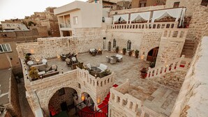 A courtyard with stone architecture, outdoor seating, and a staircase. - Ali Paşa Konağı (Mardin)