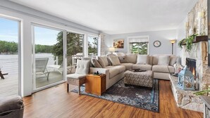 A living room with a large window, a fireplace, and a view of a lake.