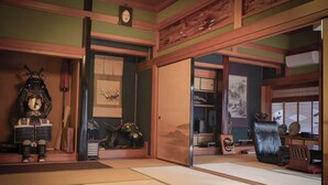 Um quarto japonês tradicional, com tatames, porta de tela shoji e uma mesa de madeira baixa com um objeto decorativo.