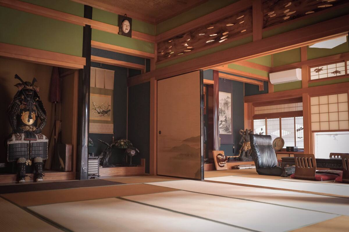 Een traditionele Japanse kamer met tatami vloerbedekking, een schuifdeur en diverse culturele decoraties.