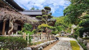 Um jardim japonês tradicional com caminhos de pedra, cercas de bambu e uma pagoda.
