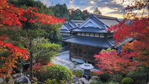 Um edifício tradicional japonês com telhado de telhas, rodeado por folhagem de outono.