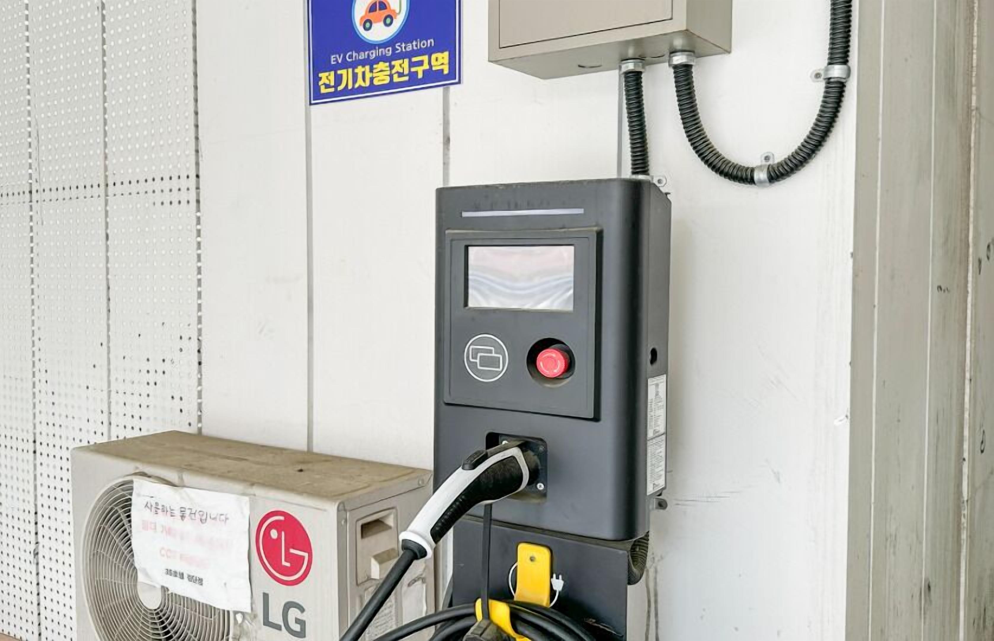 An EV charging station with a control panel, a cable, and a box labeled "LG".