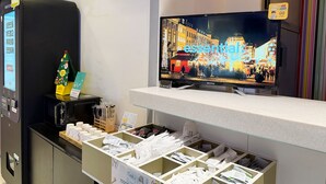 A hotel reception area with a digital screen displaying a cityscape, a vending machine, and a small Christmas tree. - Anyang 3S Fashion Hotel (Anyang)