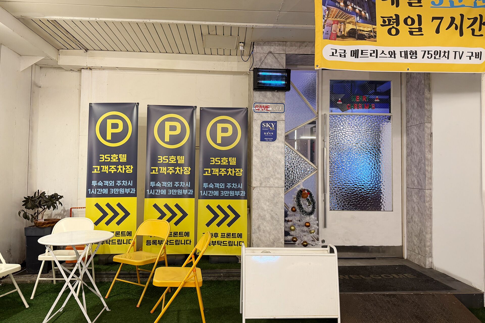 A hotel lobby with three 'P' signs indicating parking spots, a reception desk, and a Christmas-themed window display.
