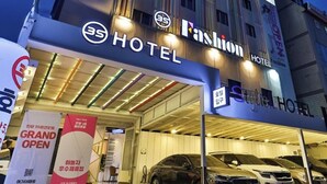 A hotel with a modern facade, illuminated signage, and a covered parking area with several cars. - Anyang 3S Fashion Hotel (Anyang)