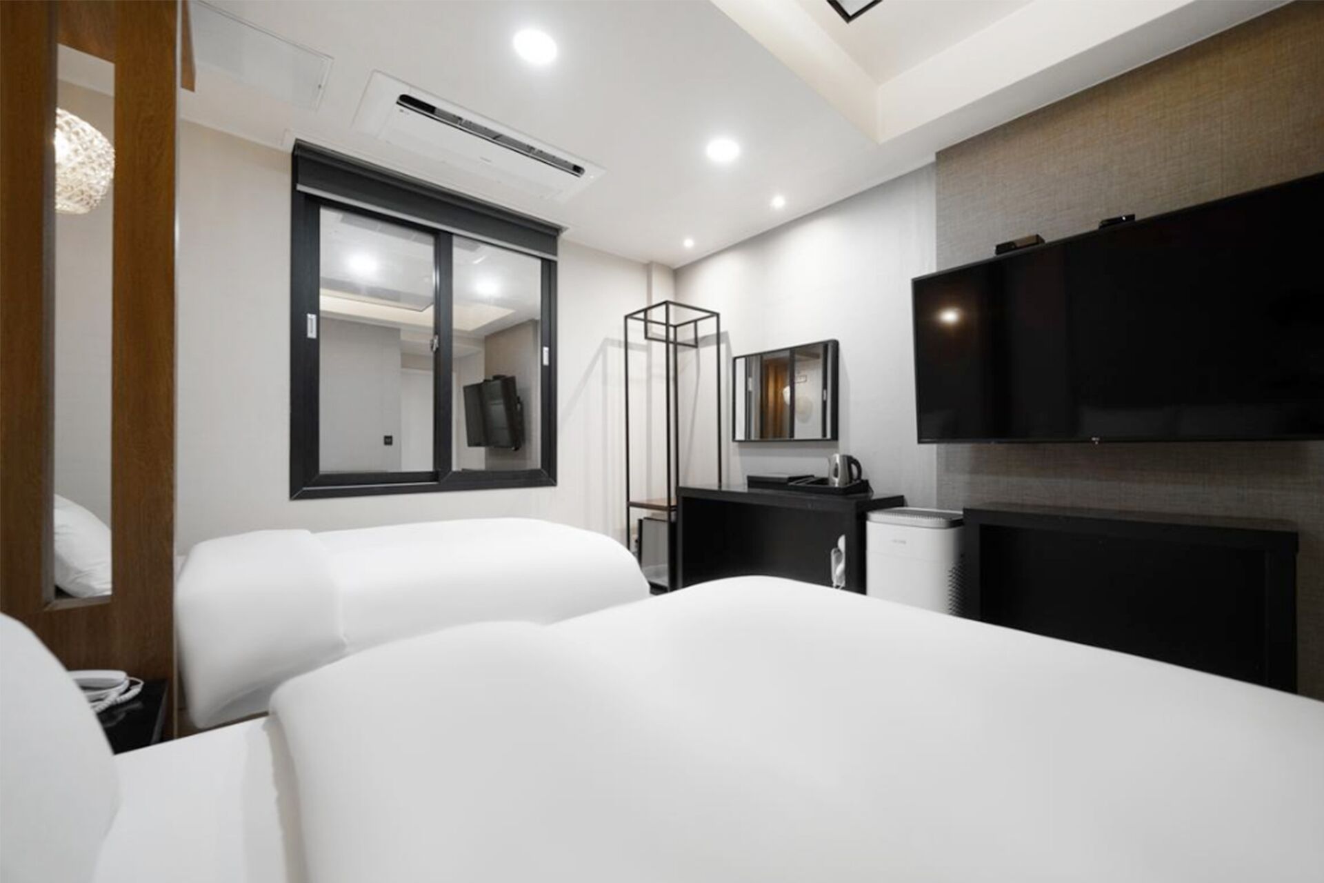 A hotel room with two beds, a TV, a desk, and a mirror.