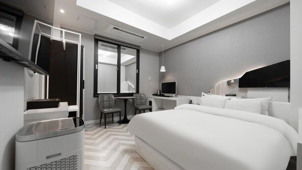 A modern hotel room with a large bed, a desk, a chair, a TV, and a ceiling light. - Anyang 3S Fashion Hotel (Anyang)