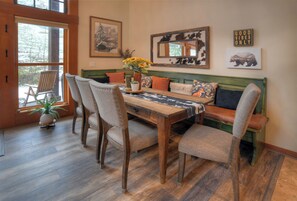 Un comedor con una mesa de madera, cuatro sillas, un banco y un espejo grande.