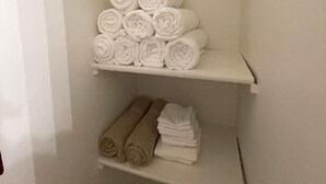A storage area with shelves holding neatly rolled towels in white and beige colors. - Waterfront legacy farm cottage house with WiFi, AC in lovely Eau Claire (Eau Claire)