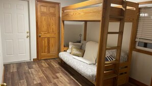 A bunk bed room with a wooden bunk bed, a sofa bed, a door, and a window. - Waterfront legacy farm cottage house with WiFi, AC in lovely Eau Claire (Eau Claire)