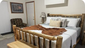A wooden bed with a bench, a plaid armchair, and a lamp. - Waterfront legacy farm cottage house with WiFi, AC in lovely Eau Claire (Eau Claire)