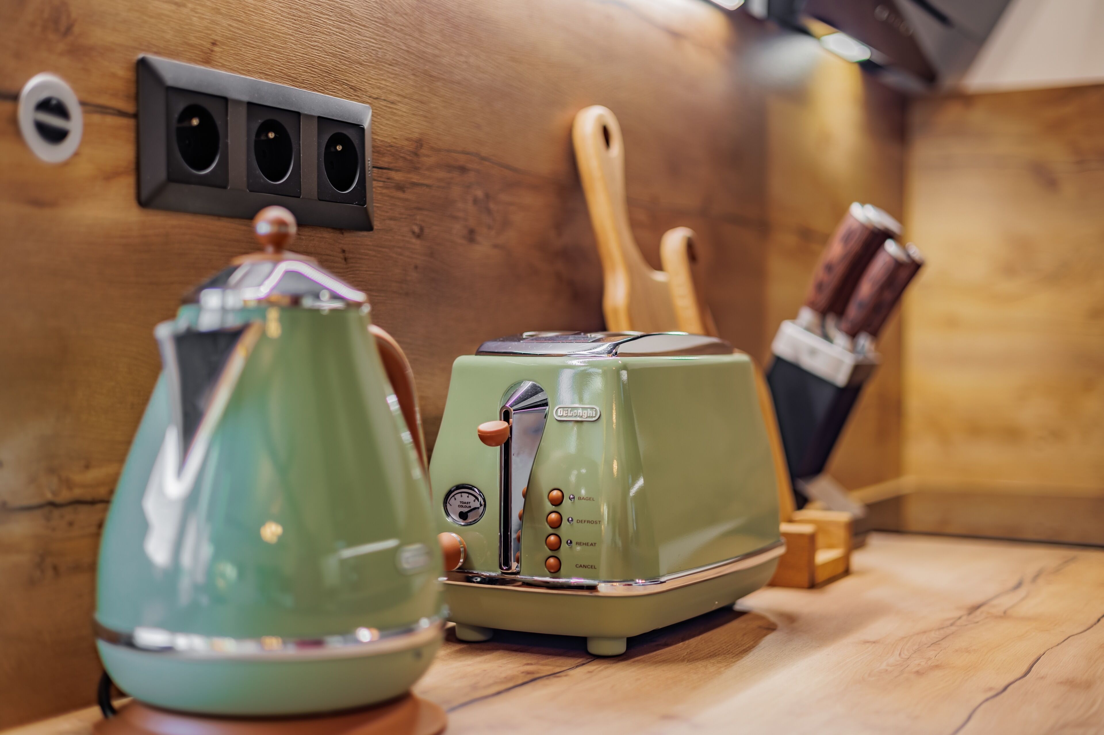 Eine Küchenzeile mit Wasserkocher, Toaster und Holzkochlöffeln auf einer Holzausziehtischplatte.