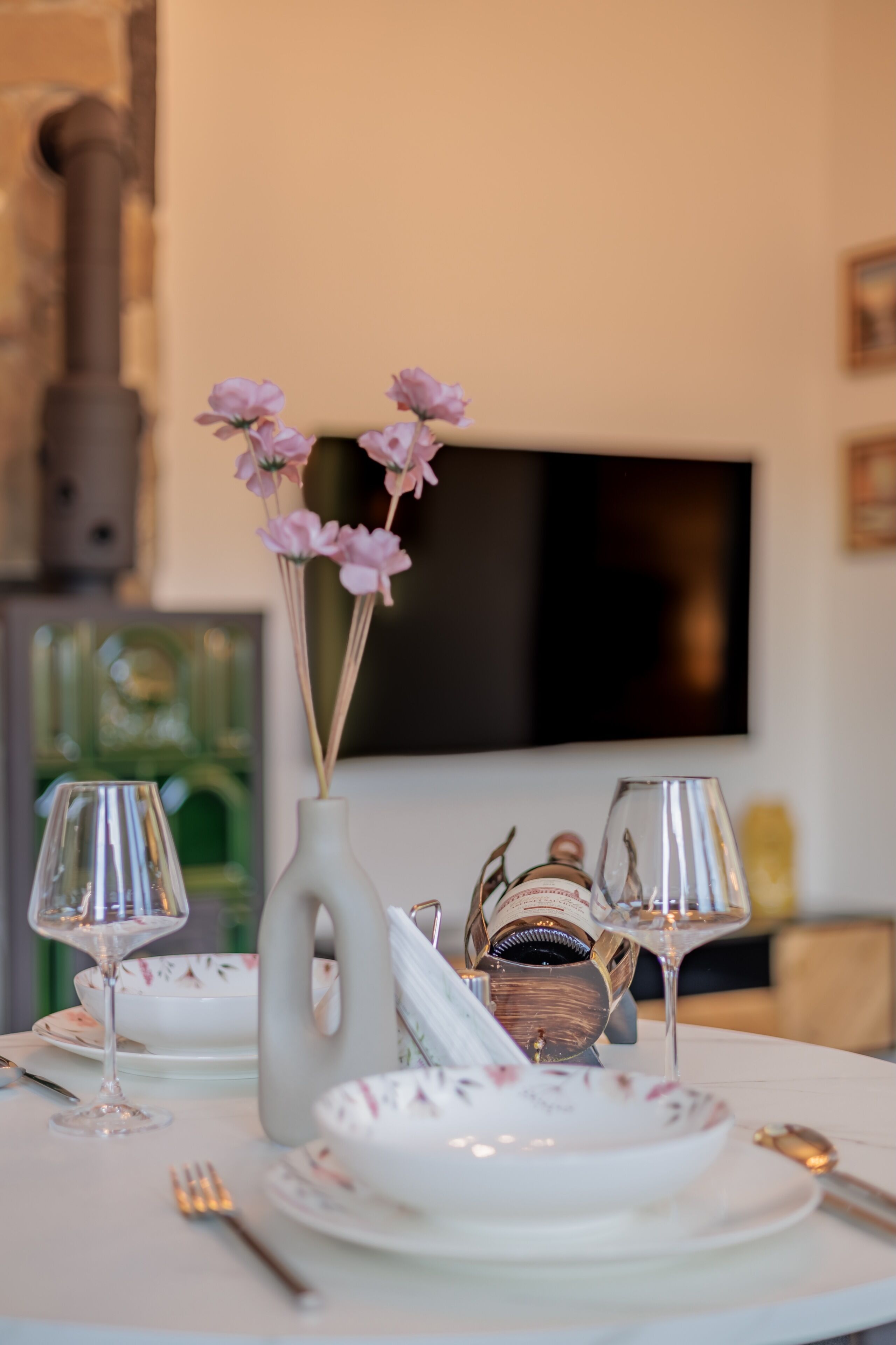 Una mesa de comedor con platos, cubiertos, un florero y una jarra decorativa.