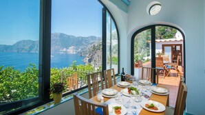 A dining area with a table set for two, overlooking a scenic coastal view. - Domus Ursula timeless charm (Praiano)