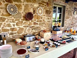 Un bufé de desayuno con diversas opciones de comida y salsas, con un fondo de pared de piedra.