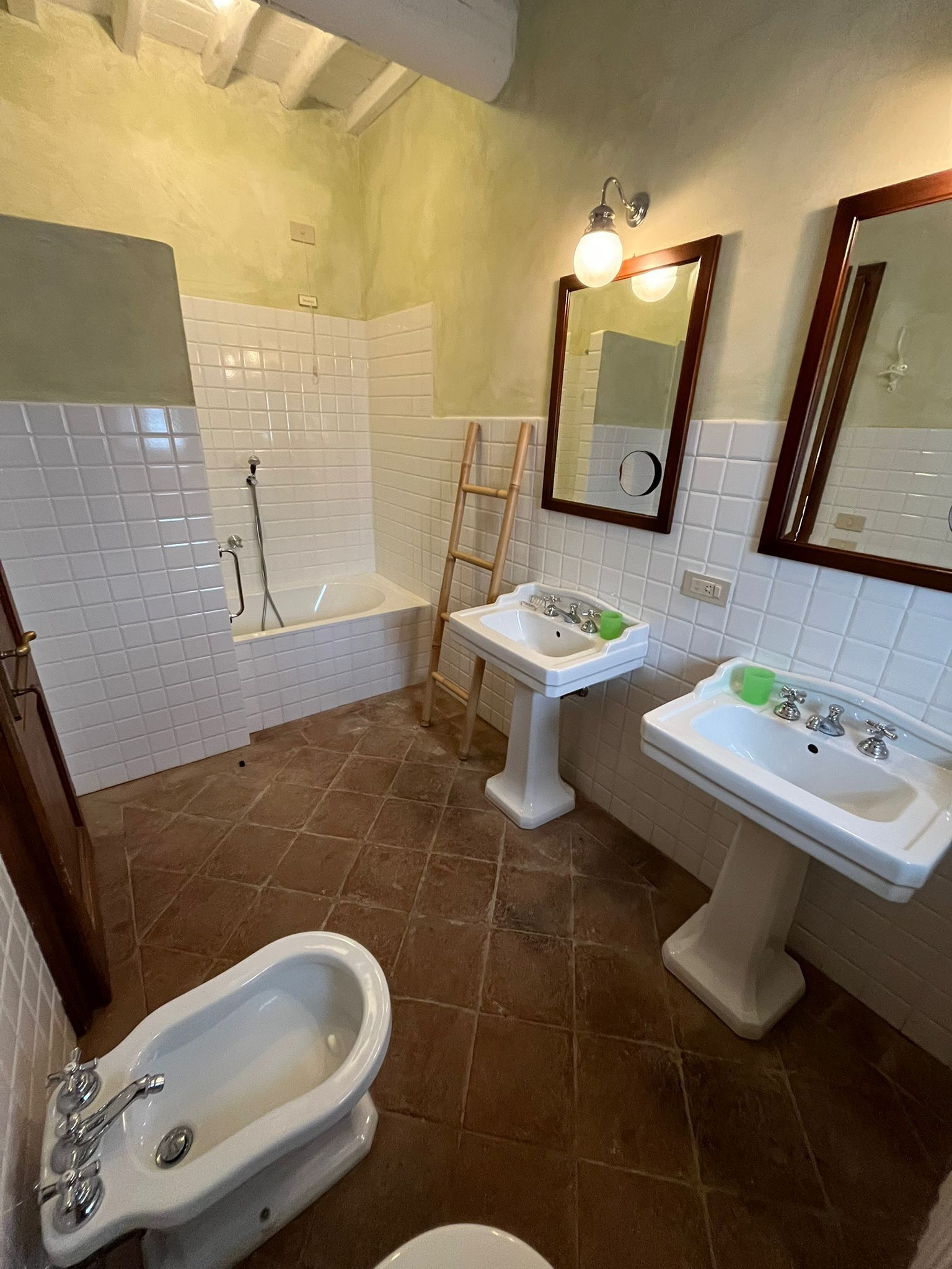 A bathroom with a bathtub, two sinks, a toilet, and a mirror.