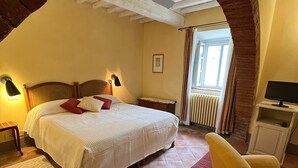 A bedroom with a large bed, a chair, a desk, and a window. - La Locanda Volpaia (Radda in Chianti)