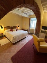 Un dormitorio con una cama grande, una silla, un escritorio y una ventana.