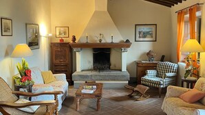 A cozy living room with a fireplace, wooden ceiling beams, and comfortable seating. - La Locanda Volpaia (Radda in Chianti)