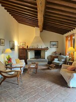 Una sala de estar acogedora con chimenea, vigas de madera en el techo y asientos cómodos.