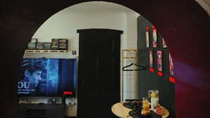 A living room with a TV displaying a movie, a coffee table with drinks, and a neon sign above. - Movie-themed apartment with large screen (Woustviller)