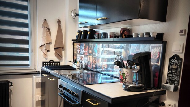 A compact kitchen with a built-in oven, a coffee machine, and a window with blinds. - Movie-themed apartment with large screen (Woustviller)