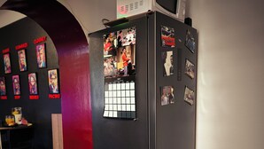 A kitchen with a black refrigerator, a microwave on top, and a calendar on the door. - Movie-themed apartment with large screen (Woustviller)