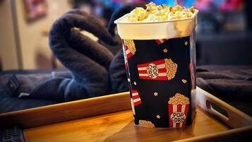 A popcorn container on a tray with a TV in the background displaying a red and blue screen.