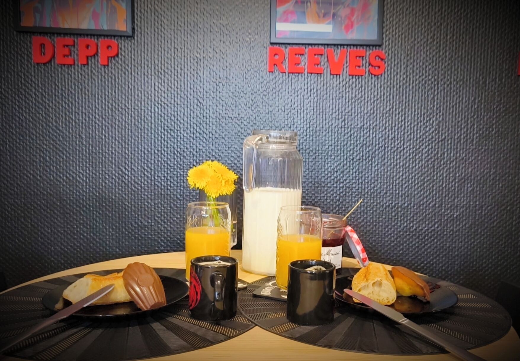 Desayuno con un muffin, una taza de café, jugo y una jarra de leche sobre una mesa con individuales.