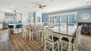 A spacious kitchen with a large island, wooden chairs, and a dining table.