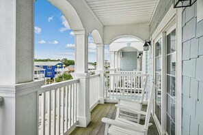 Eine überdachte Veranda mit weißen Geländern und Blick auf ein blaues Gebäude im Hintergrund.