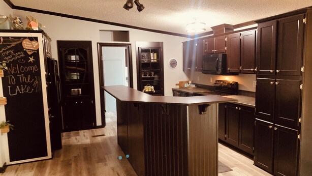 A modern kitchen with dark wood cabinets, a central island, and a built-in microwave.