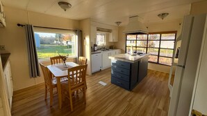 A kitchen with wooden flooring, a dining table with chairs, a built-in island, and a refrigerator. - Private space in Forks with AC, high-speed Wi-Fi, covered BBQ, outdoor fire pit (Forks)
