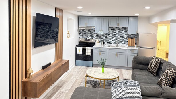 A modern living room with a sofa, a coffee table, and a TV mounted on the wall. - Charming 2-bedroom apartment in fabulous Chicago with WiFi, Game Space (Chicago)
