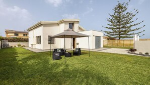 Une maison moderne dotée d’un patio, de mobilier d’extérieur et d’un grand arbre.