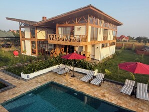 Ein zweistöckiges Haus mit Pool, Sitzgelegenheit im Freien und einem gepflegten Garten.