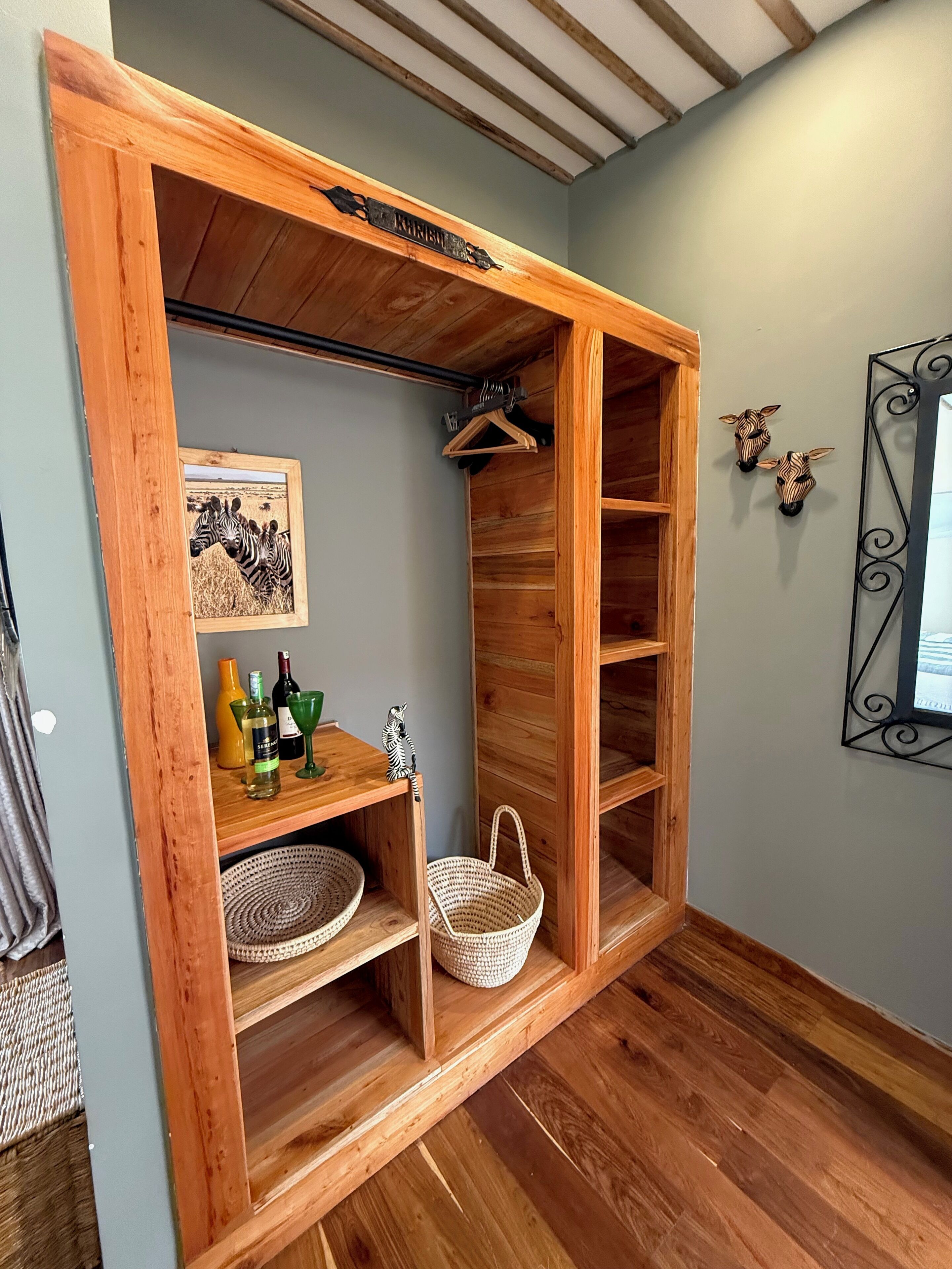 A wooden storage unit with shelves, a hanging rack, and a framed picture of zebras.