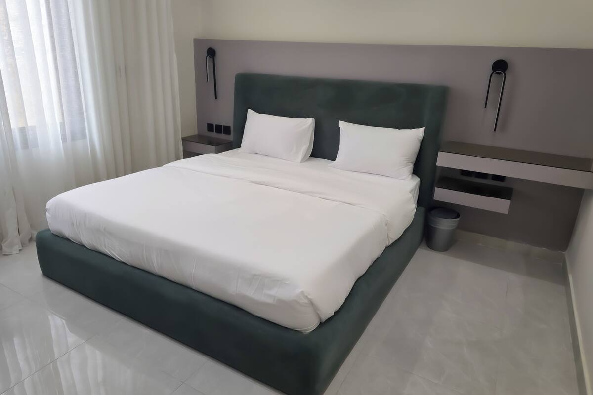Ein modernes Hotelzimmer mit einem großen Bett, einem Nachttisch und einem Mülleimer.