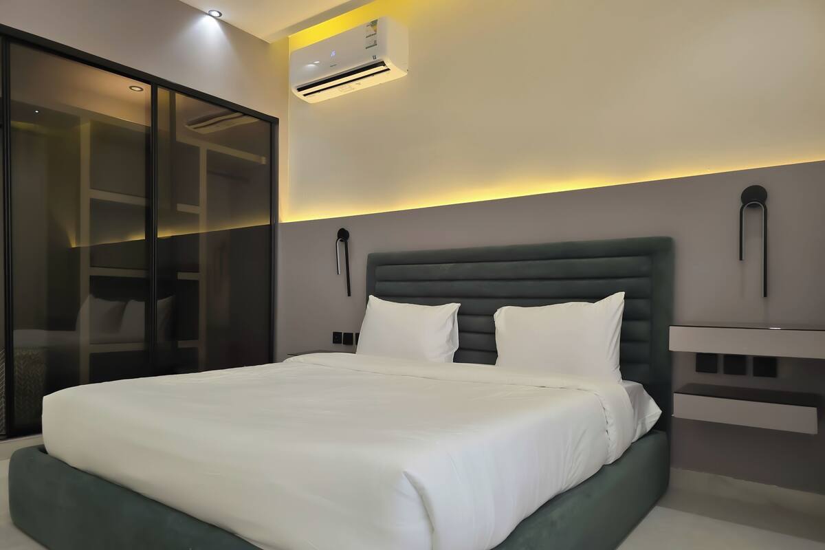 Ein modernes Hotelzimmer mit einem großen Bett, einem Kleiderschrank und einem Nachttisch.