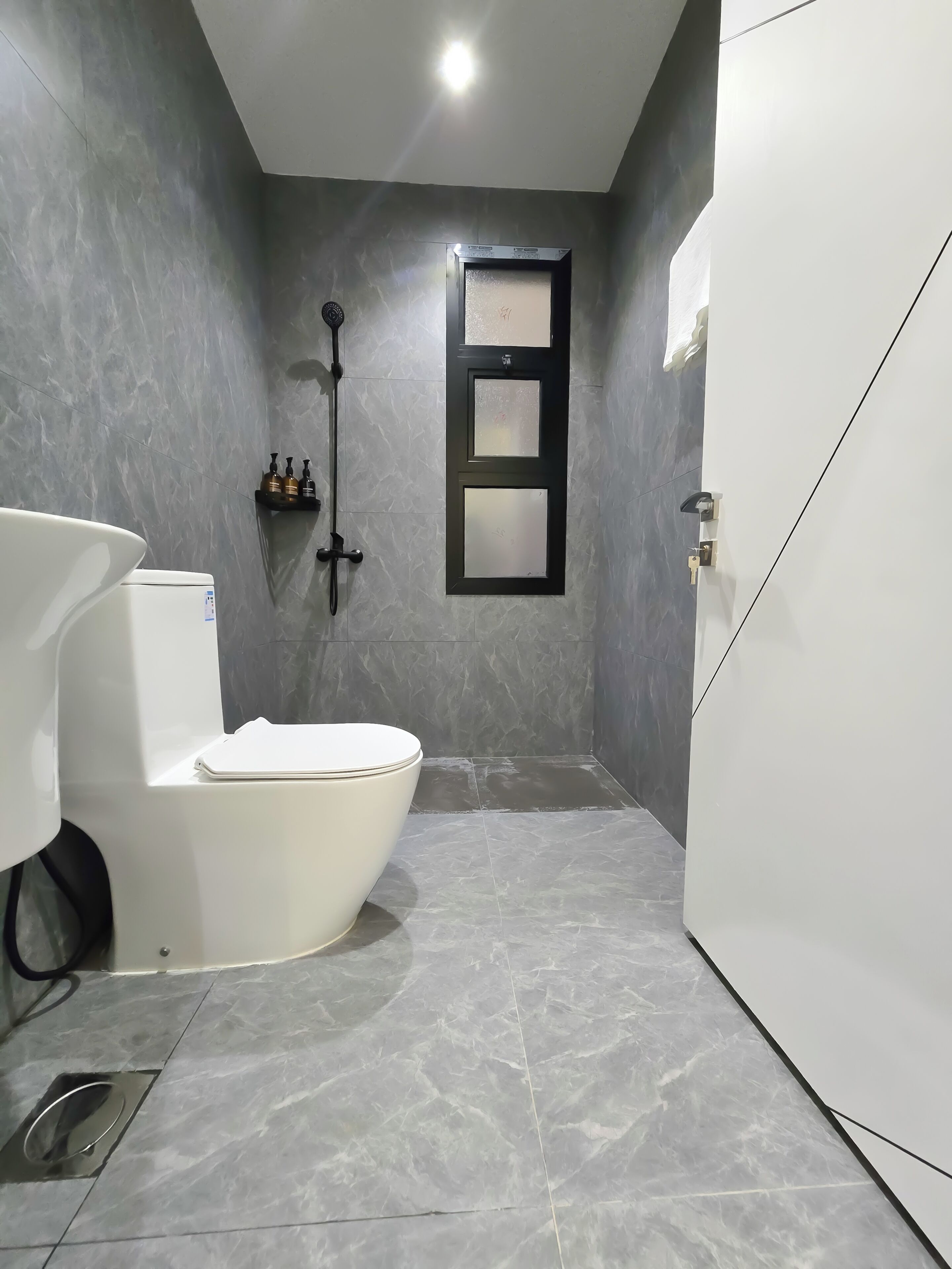 A bathroom with a toilet, a shower, and a sink.