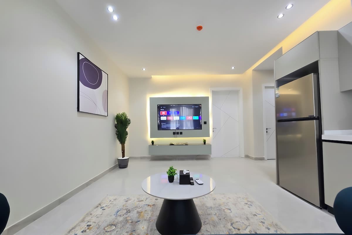 Eine moderne Küche mit Einbaukühlschrank, einem flachbildfernseher an der Wand und einem Essbereich mit rundem Tisch und Stühlen.