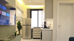 A modern kitchen with a built-in refrigerator, a sink, and a stove. There is a dining area with a table and chairs, and a TV mounted on the wall. - Hometel NRJS B Ruh (Riyadh)