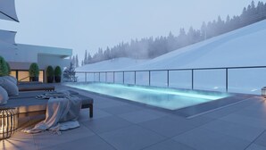A modern outdoor pool area with a glass barrier, seating, and a view of a snowy hillside. - Apartment in Berwang With Ski-in/ski-out (Berwang)